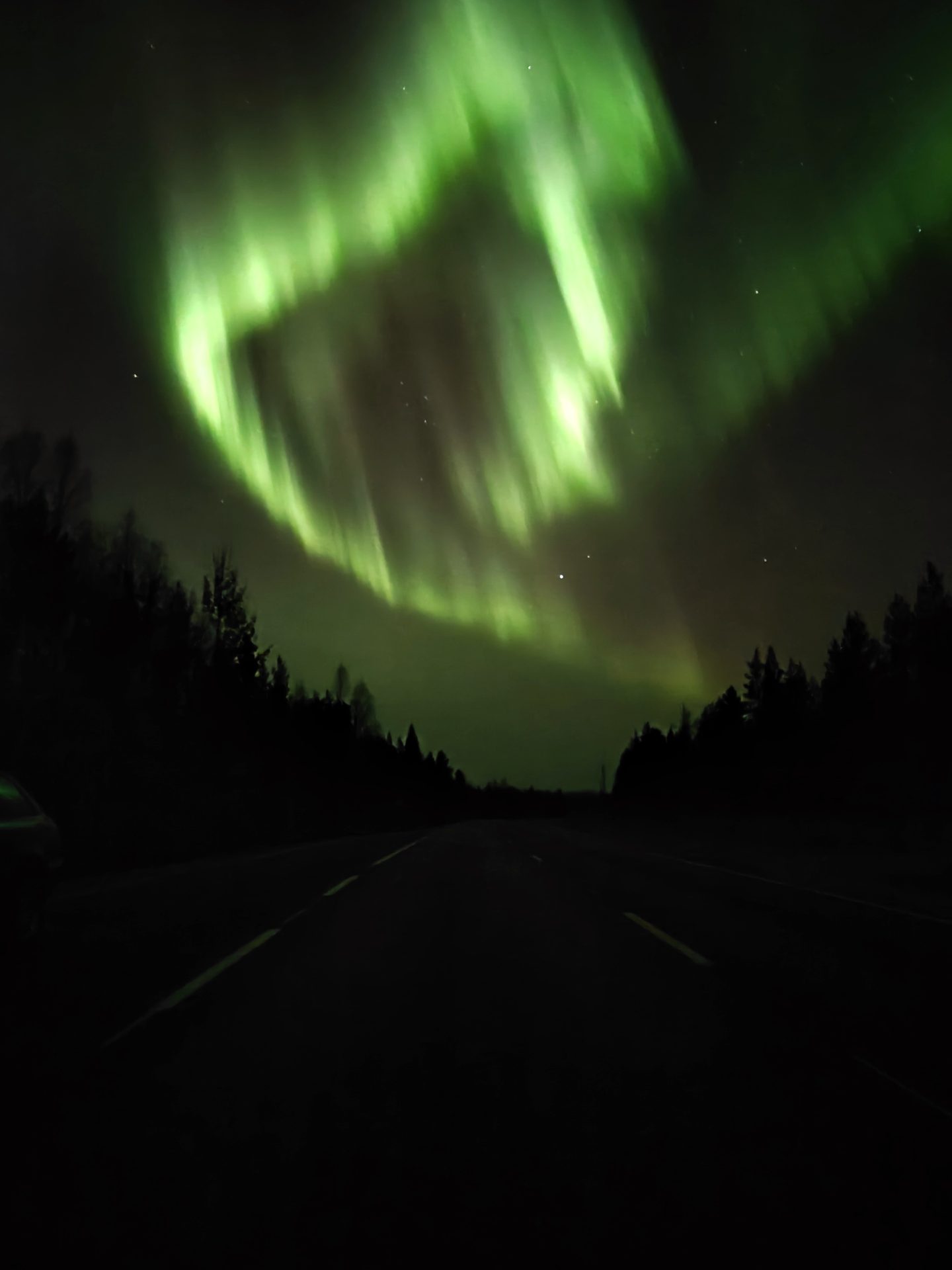 A bright green aurora corona directly overhead on a Rovaniemi backroad, seen on one of our tours